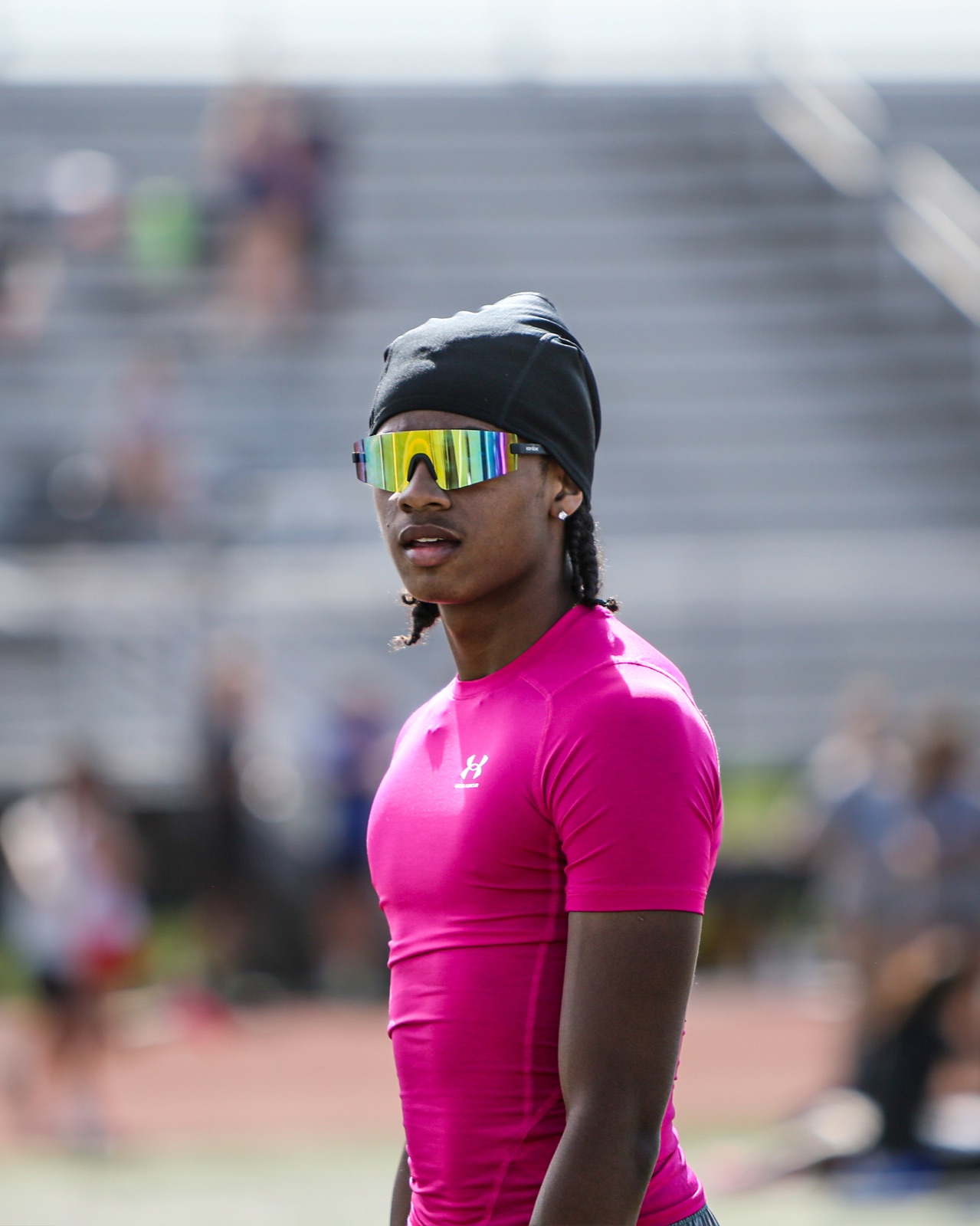 Track athlete wearing a bright pink shirt and reflective sunglasses