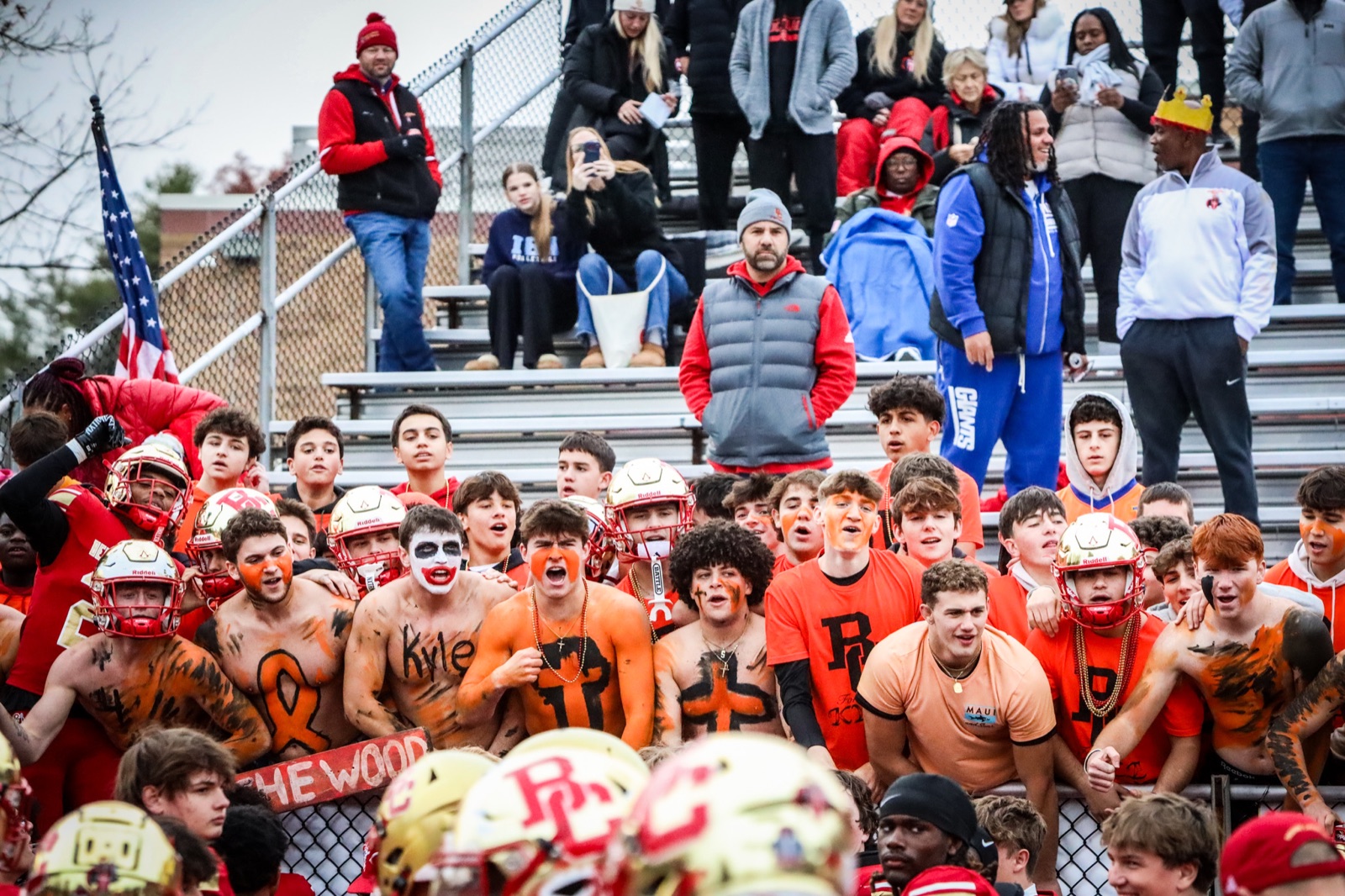Painted student section cheering behind a football sideline